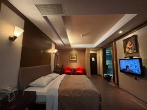 Habitación de hotel con cama y TV en Hua Xiang Motel - Da Chang en Kaohsiung