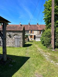 an old stone building with a grass yard in front at La Maison Mignonne in Azerables