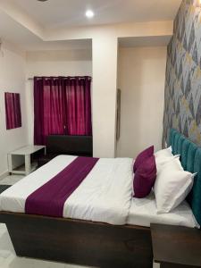 Schlafzimmer mit einem Bett mit lila und weißen Kissen in der Unterkunft Hotel Paradise Inn in Indore