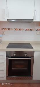 a stove top oven in a kitchen with white cabinets at Apartamento Oliva playa a escasos metros del mar in Oliva +11 photos