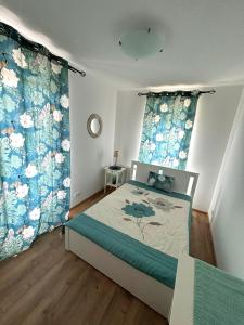 a bedroom with a bed with blue and white curtains at Club218 Holiday Apartman Siófok in Siófok