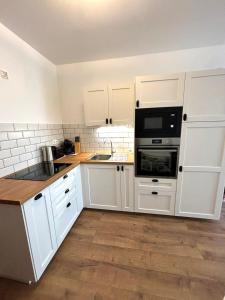 a kitchen with white cabinets and black appliances at Club218 Holiday Apartman Siófok in Siófok
