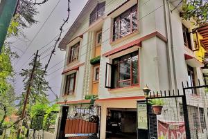 a large white building with windows and a fence at Hotel Marc Mall Road Shimla - Family Friendly & Parking - A Four Star Luxury Hotel Mountain View in Shimla