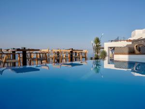 - Vistas a la piscina de un complejo con mesas y sillas en Stella Rocca A Mare en Imerovigli
