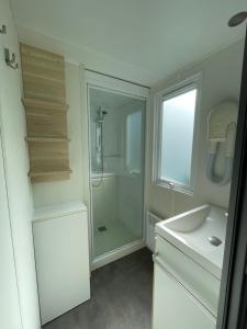 a white bathroom with a shower and a sink at VeniseOuest Hôtellerie de Plein Air in La Ferté-Bernard