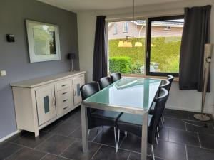une salle à manger avec une table et des chaises en verre dans l'établissement Holiday Home Friesland near the Wadden Sea with Wifi and 3 Bedrooms, à Tzummarum