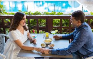 un hombre y una mujer sentados en una mesa comiendo comida en Hotel Atlantic, en Lignano Sabbiadoro