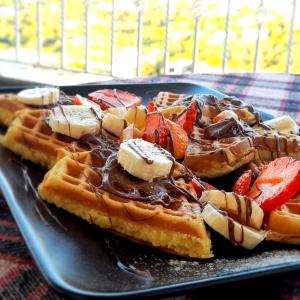 a plate of waffles with chocolate and strawberries at Vila Marjana in Sarandë