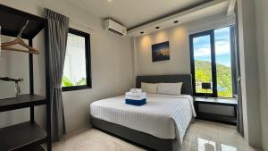 a bedroom with a bed and two large windows at Naiwok Hills Resort in Haad Pleayleam +77 photos