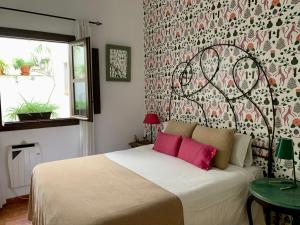 a bedroom with a bed with pink pillows on it at Apartamentos Los Patios de la Judería in Córdoba