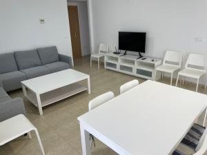 a living room with a couch and a tv and chairs at Apartamento ático en Denia in Denia