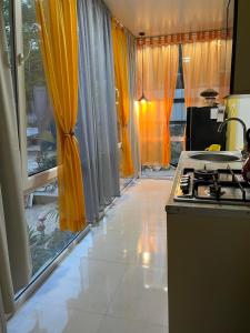 a kitchen with yellow curtains and a stove in it at Me and grandfather-მე და პაპა in Dedoplis Tskaro