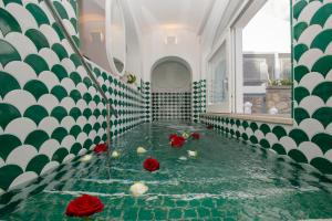 ポジターノにあるVilla Francesco Luxury Suitesの緑と白の壁の部屋にある、水の中に花が飾られた部屋