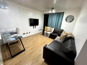 a living room with a black couch and a television at Amazing Earls Court 2 bed Flat with Balcony in London
