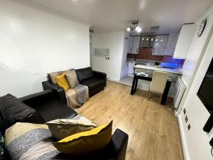 a living room with a couch and a table and a kitchen at Amazing Earls Court 2 bed Flat with Balcony in London