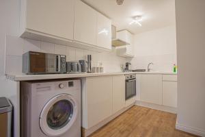 a white kitchen with a washing machine in it at Beautiful Flat in Halifax - Perfect for Long Stays in Halifax