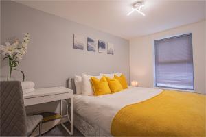 1 dormitorio con cama con almohadas amarillas y escritorio en Beautiful Flat in Halifax - Perfect for Long Stays, en Halifax