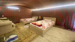 two beds in a room with red walls at private farmhouse Tent Room in Al Rahba