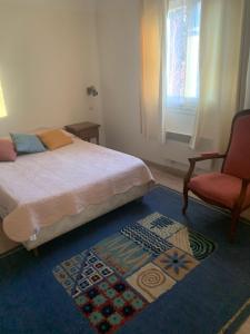 una camera con un letto e una sedia e una finestra di Albizia a Vernet-les-Bains