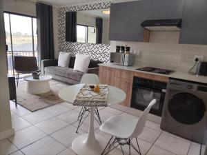 a kitchen and living room with a table and chairs at The Lagoon Exquisite Apartments in Pretoria