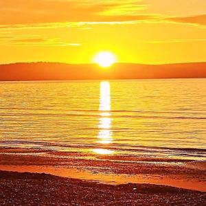 a sunset on the beach with the sun setting at Penn House Hotel in Weymouth