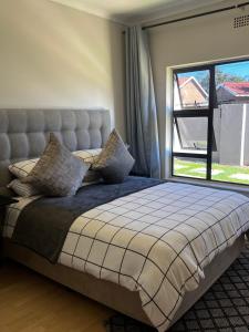 ein Schlafzimmer mit einem großen Bett und einem großen Fenster in der Unterkunft Ekhaya in Kimberley