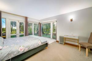 Schlafzimmer mit einem Bett, einem Stuhl und Fenstern in der Unterkunft Pukekohe Farm House 5min to Town Centre in Buckland