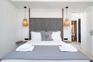a bedroom with a large bed with two towels on it at CUORE SANTO SUITES in Fira