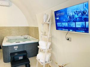 een badkamer met een bad en een tv aan de muur bij The Loft Luxury Room Suite con minipiscina in Adelfia