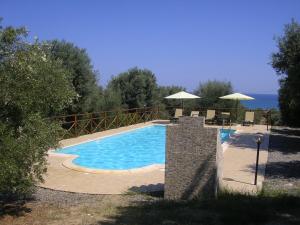 - une piscine avec des chaises et des parasols au bord de l'eau dans l'établissement Agriturismo Torre Rinusa, à Mandatoriccio Marina