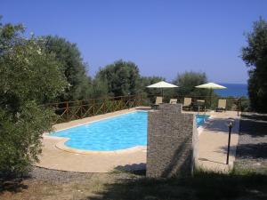 a swimming pool with chairs and umbrellas next to the water at Agriturismo Torre Rinusa in Pietrapaola