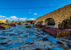 un patio de piedra con bancos y una pared de piedra. en bit mumia house & restaurant, en Kerak