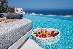 a basket of food sitting on a bed next to a pool at CUORE SANTO SUITES in Fira