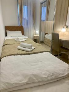 two beds in a hotel room with towels on them at Jagodina Wing Apartman 2 in Jagodina