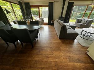 un soggiorno con tavolo, divano e sedie di Dubbele chalet op recreatiepark Topparken op de Veluwe in Beekbergen met grote vrije tuin en eigen parkeerplaats a Beekbergen
