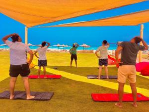 Dawwār ‘Abd al Qādir Qāsim的住宿－Borg El Arab Beach Resort，一群人在海滩上做瑜伽
