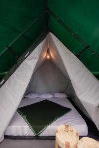 ein grün-weißes Zelt mit einem Bett darin in der Unterkunft Wonderwoods Tent Camping Munnar in Munnar