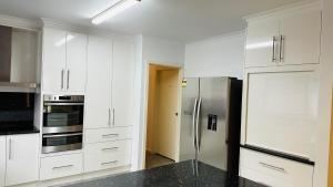 a kitchen with white cabinets and a stainless steel refrigerator at Early Australian Motor Inn in Mildura