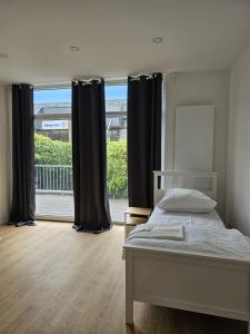 a bedroom with a bed and a large window at SFN Home Stay in Bergisch Gladbach