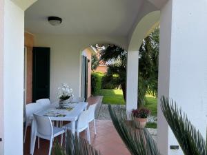 a patio with a white table and white chairs at Villa I Giardini del Conero con ombrellone in spiaggia in Porto Recanati