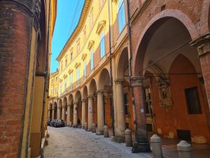 an alley in an old town with buildings and cars at Luxury Apartment in Palazzo Spada in Bologna