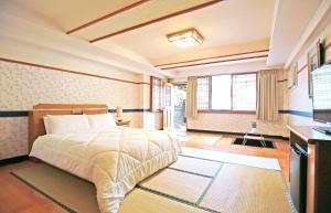 a bedroom with a bed and a desk and windows at Phoenix Pavilion Hot Spring Hotel in Taipei