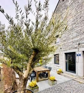ein Baum vor einem Steingebäude mit einem Picknicktisch in der Unterkunft L'Héritage de Durbuy in Durbuy