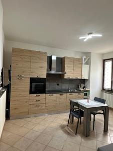 a kitchen with wooden cabinets and a table in it at la corte di seba milano malpensa in Cardano al Campo