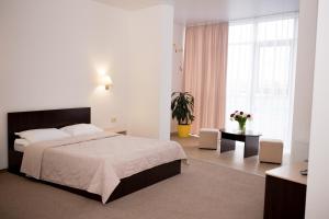 1 dormitorio con cama, mesa y ventana en Ostrov River Club en Novosëlovka