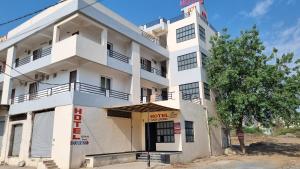 a white building with a tree in front of it at Hotel Mayur Inn in Udaipur