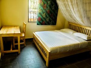 een slaapkamer met een bed, een tafel en een raam bij Mianzi Guest House in Kisoro
