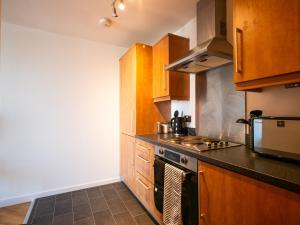uma cozinha com armários de madeira e um forno com placa de fogão em The Safari Suite Luxury Apartment Milton Keynes em Milton Keynes