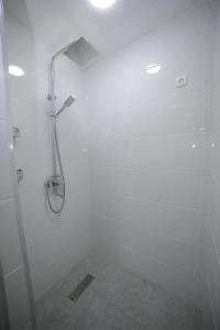 La salle de bains blanche est pourvue d'une douche avec une porte en verre. dans l'établissement Al Hilal Hostel, à Samarcande