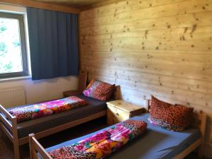 two beds in a room with wooden walls at Appartement Grünfelder in Oberperfuss